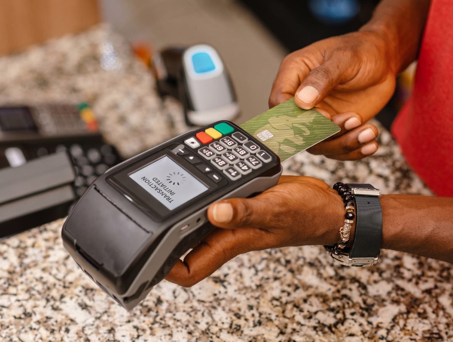 A card going into a POS terminal at a counter, hands and screen in frame. Trust, at the moment it is decided.
