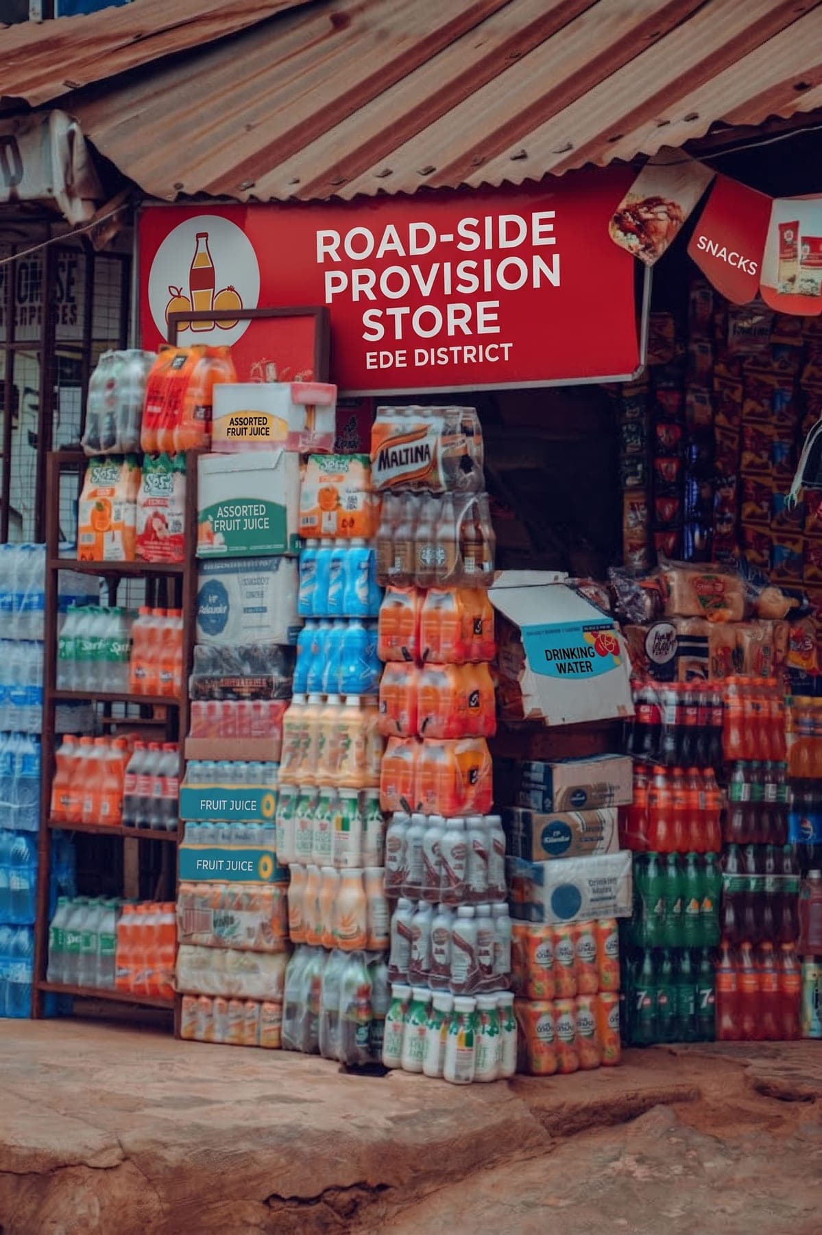 A roadside provision store stacked with crates of drinks, where shelf space is the whole battle.