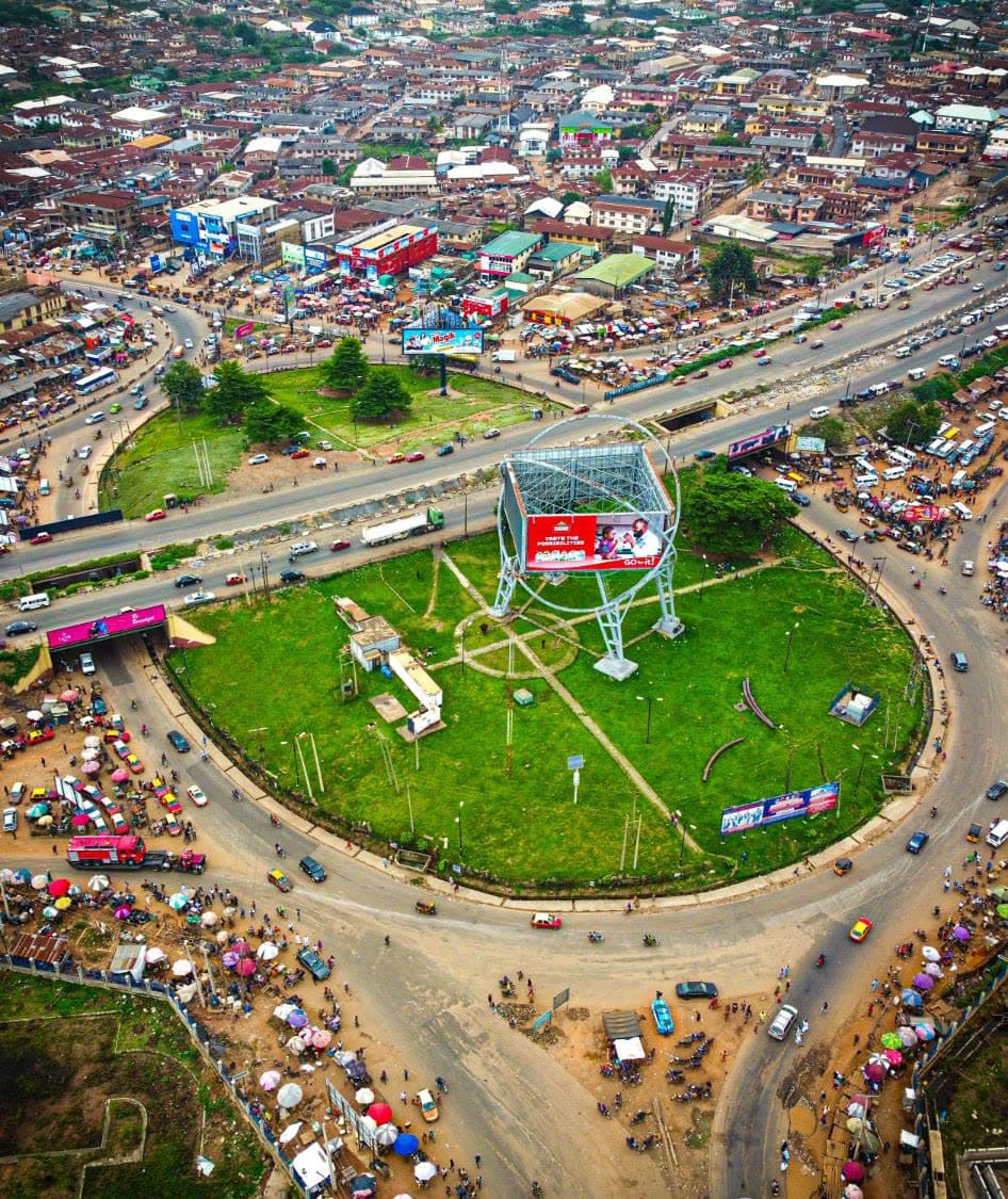 A roundabout billboard at a busy junction, shot from the air.